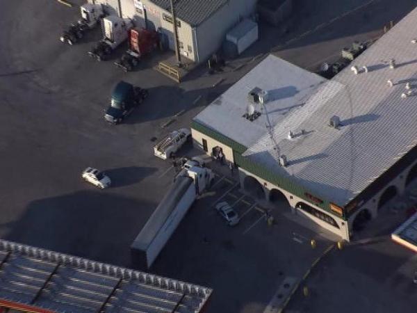 A tractor trailer rolls into a car and a building in Dunn