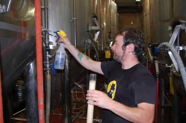Lonerider Brewing Company's head brewer Galen Smith cleans the tank before and after taking a sample from the fermentor. 