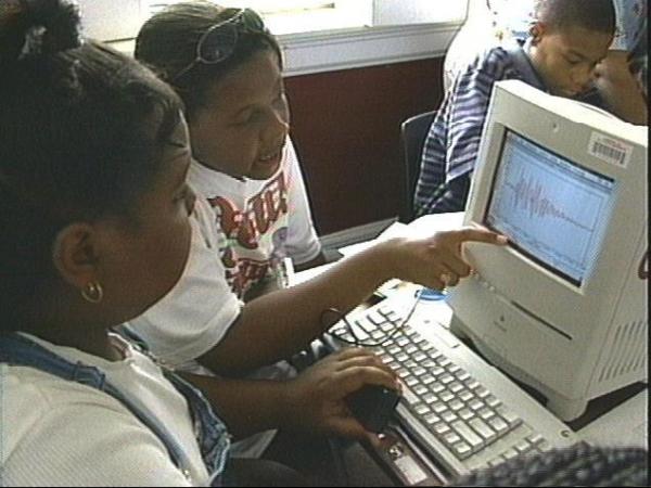 A group of students gather around a computer to learn about science