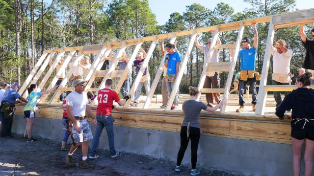 Michelle Thurston, at center in blue shirt, feels the thrill as the first wall of her family's new house rises around her, hoisted by volunteers with Cape Fear Habitat for Humanity. Many of the volunteers were college students who were taking their spring break to join the Collegiate Challenge.