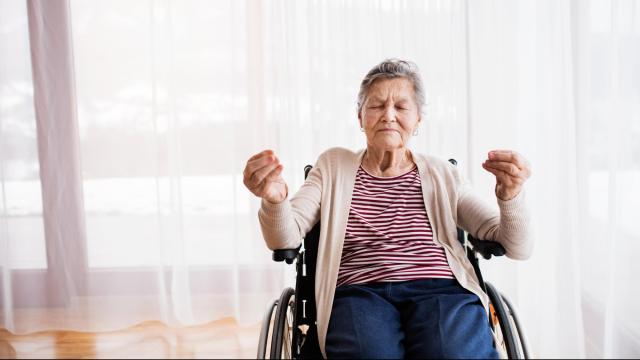 Senior Woman In Wheelchair At Home, Meditating.