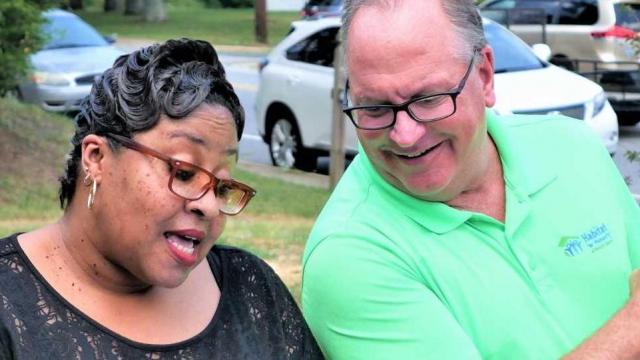 Khadijah Shabazz, left, and Mike Campbell, executive director of Habitat for Humanity of Forsyth County, lead the dedication of a new home in Winston-Salem for Shabazz and her daughter Sakile.