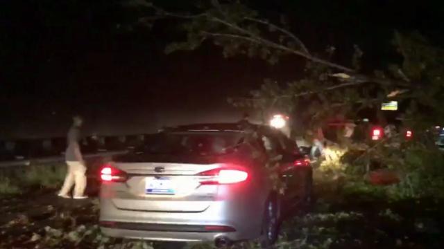 Drivers stop to pull downed tree off car on US 64