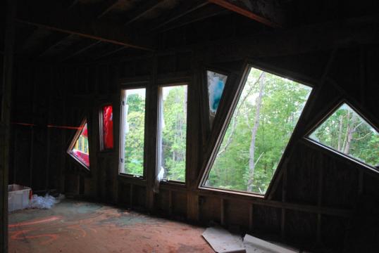 Inside view looking out through six random shaped windows. All are busted out and evening light filters into the second floor of the castle. Taken in Rougemont, North Carolina on September 11, 2019 by Katie Clark.