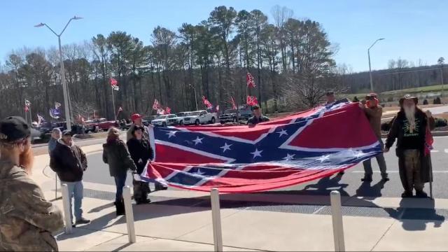 Protesters at a polling site during early voting wave Confederate flags, shout slurs