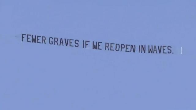 Plane flies over ReOpen NC protest with counter protest message.