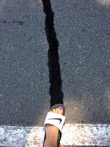 A crack nearly as wide as a human foot could be seen in the asphalt on a road.