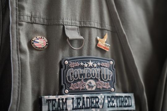 Cowboy's wilderness vest is decked out with his nickname and pins. 