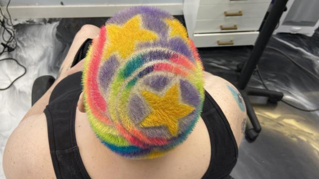 Client @rainbowtatgirl on Instagram, current hairstyle consists of a colorful haircut with stars and a rainbow that matches her tattoo.